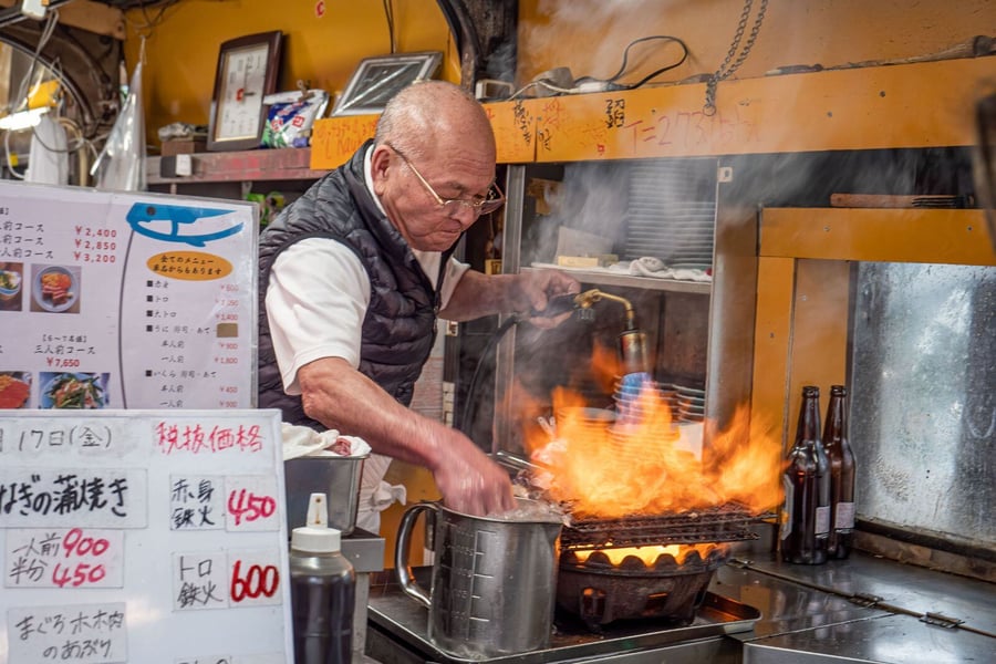 Una foto di toyo-san che cuoce il tonno con la fiamma ossidrica e lo gira a mani nude